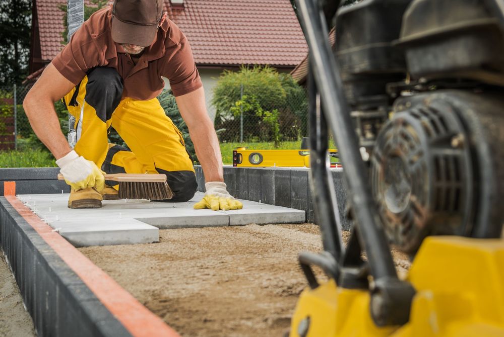 Residential Pathway Concrete Bricks Paving by Worker. Compacting Machine in a Front.