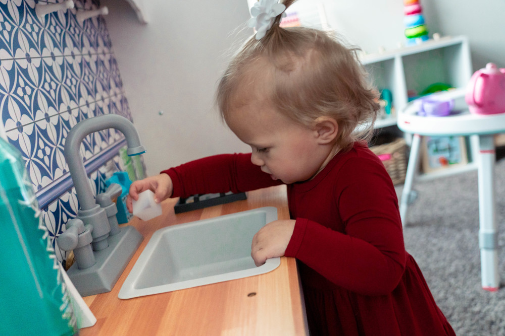Toddler playing in play kitchen