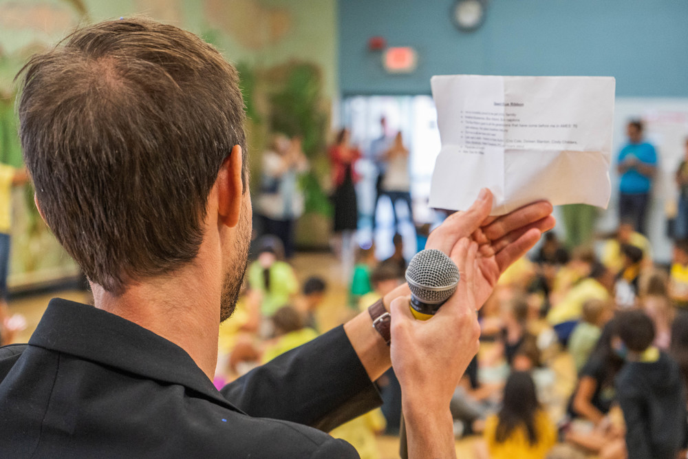 Principal Dr. Dietger De Maeseneer clapping with microphone in front of students