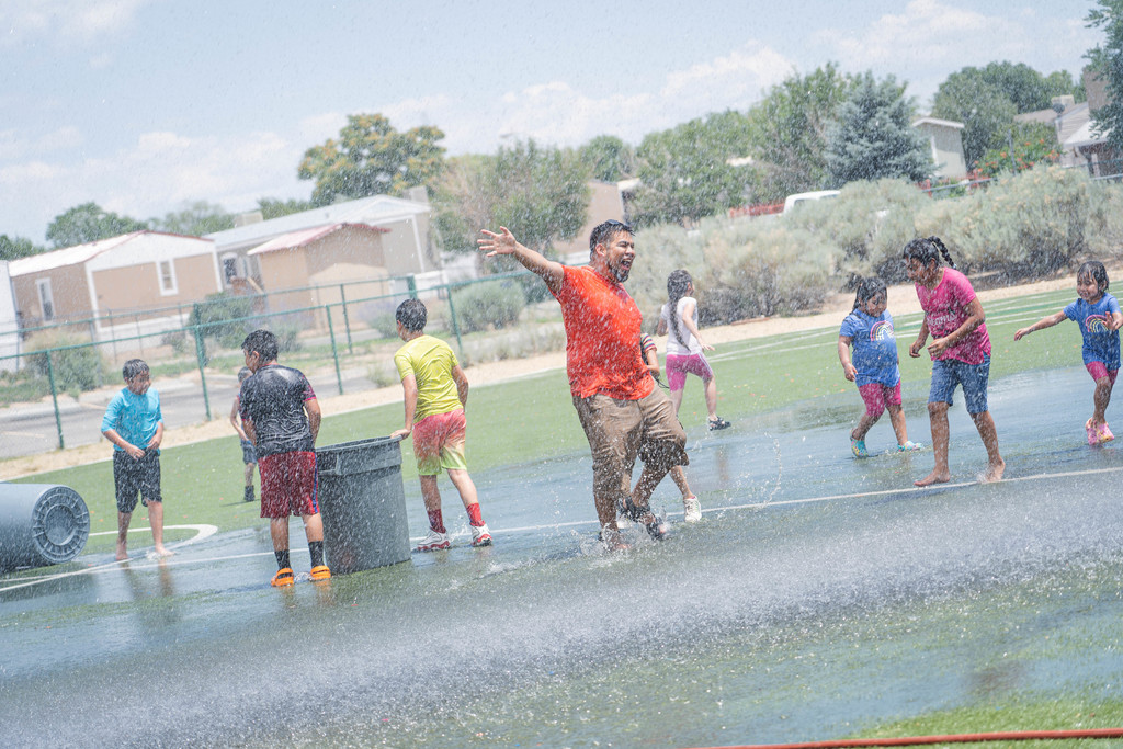 Teacher Bryan Cruz smiling with joy playing in the downfall of water with students