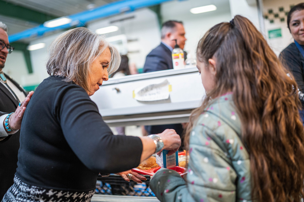 Governor Michelle Lujan Grisham handing milk to female student