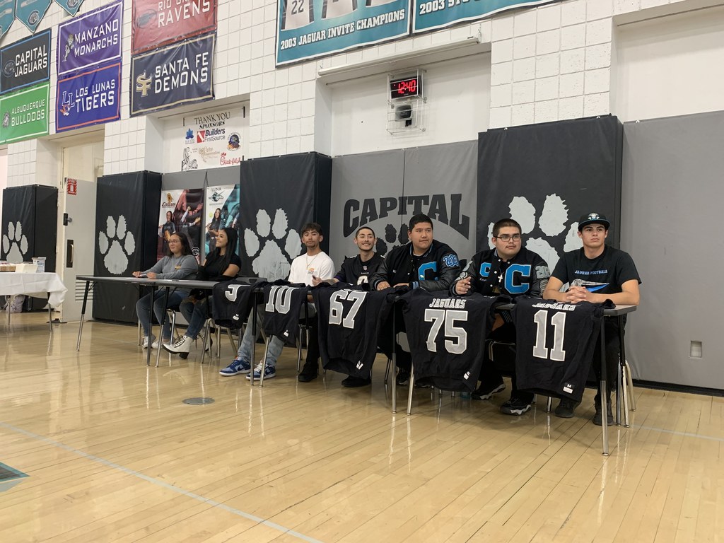 Capital High School athletes sitting at a table in the gym signing their Letter of Intent