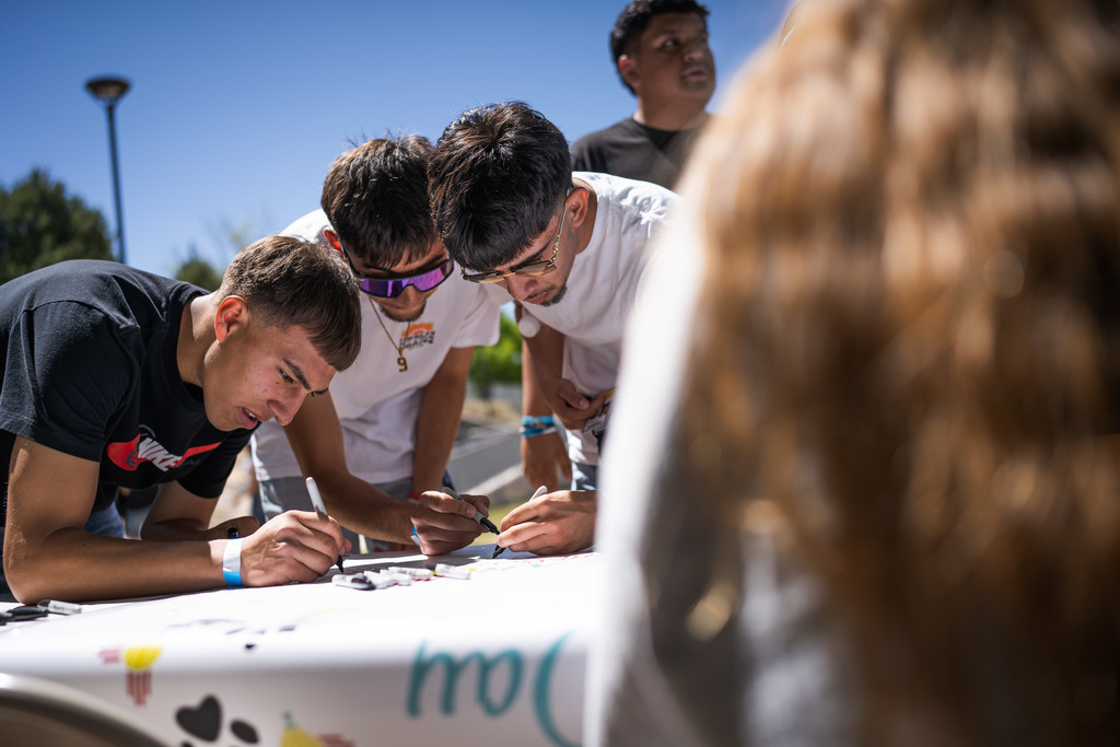 3 male students signing a banner