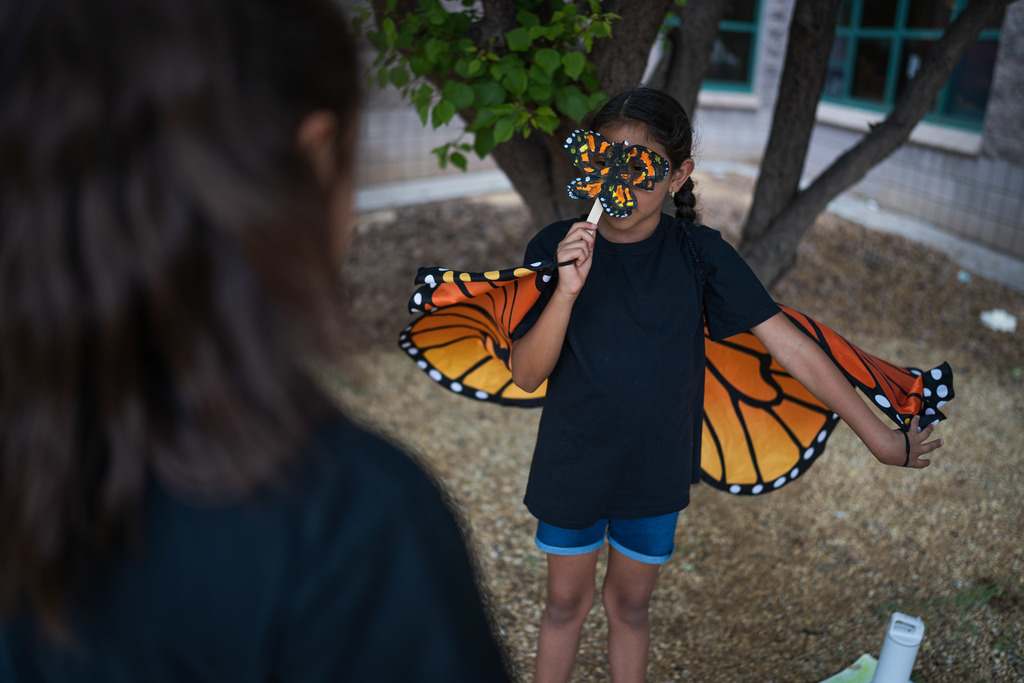 Student dress as a Monarch Butterfly telling another student facts about the butterfly