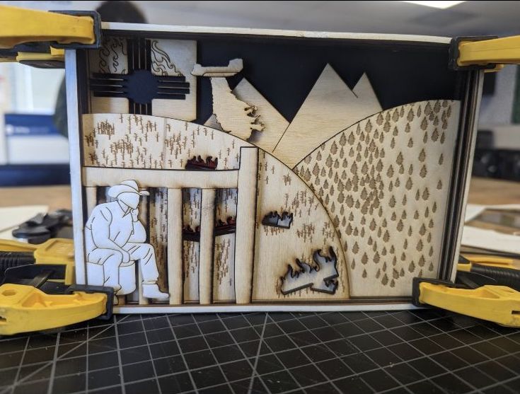 A laser-printed piece of art, made of wood, depicting a firefighter overlooking fires in the mountains