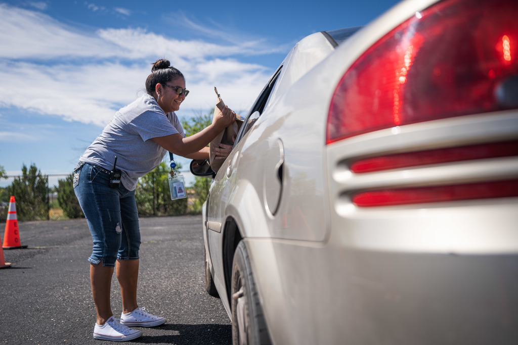 female giving school supply bag to driver of a car