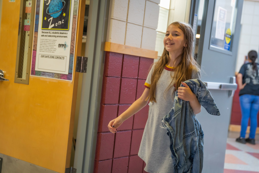 female student smiling walking through door
